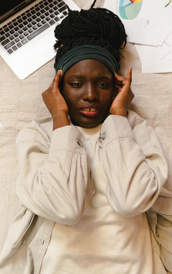 erika t kendrick woman laying on bed with laptop and papers looking anxious-min woman laying on bed with laptop and papers looking anxious